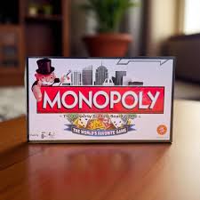 Monopoly game box on a wooden table with a blurred background available at Juniors Toys