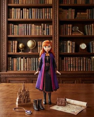 Doll with red hair and purple cloak standing in front of a bookshelf - Princess Anna Doll at Juniors Toys
