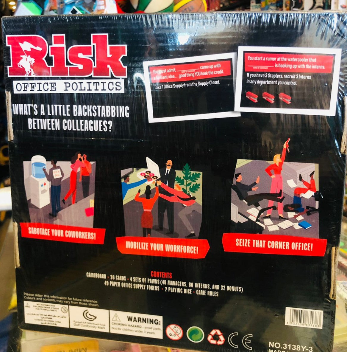 Risk Office Politics game box with illustrations and text on a blurred background available at Juniors Toys
