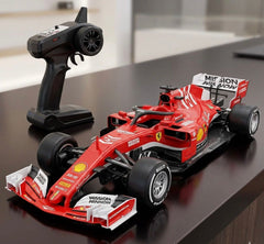 Red Formula 1 car model with remote control on a reflective surface available at Juniors Toys