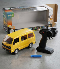 Yellow toy van with remote control and screwdriver on a gray surface, Junino packaging in the background available at Juniors Toys