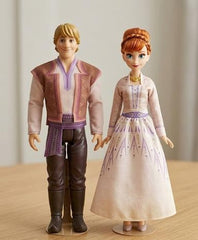 Two dolls, one male and one female, standing on a wooden surface with a neutral background Available at Juniors Toys