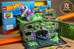 Detailed view of the open Hot Wheels Ghost Garage playset showing the green haunted garage, the purple phantom figure, and two cars on track pieces with accessories available at Juniors Toys