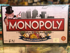 Monopoly board game box with colorful graphics and text on a blurred background available at Juniors Toys